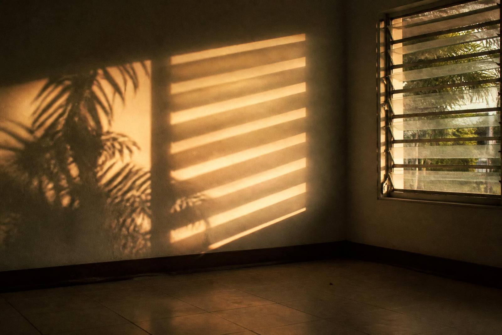 Late afternoon light falling across a worn armchair and a half open window